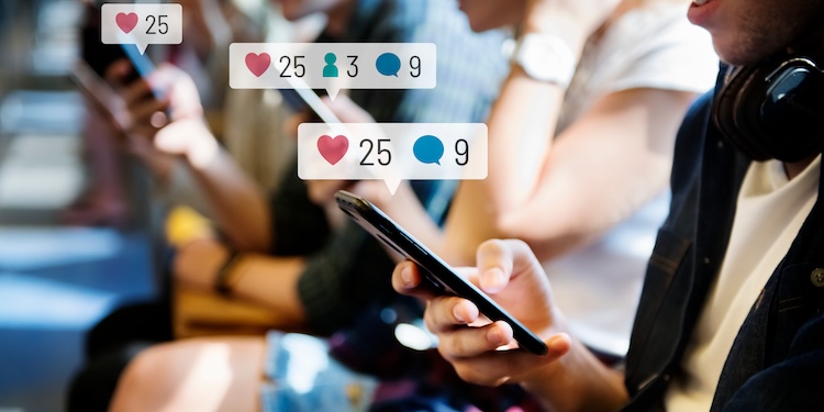 A row of people looking at their cellphones with graphics above their phones indicating likes, shares, and questions.