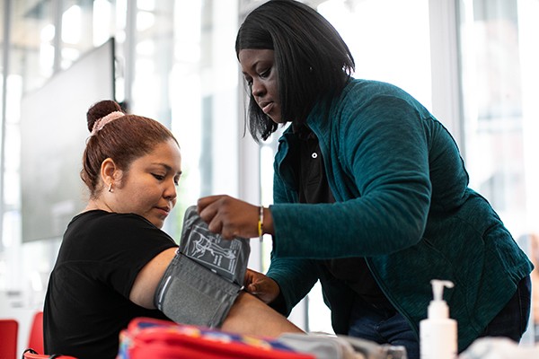 A Columbia University staffer does blood pressure testing at a Community Day event on the Manhattanville campus.