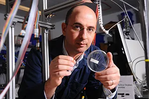 scientist at work in lab holding a microscopic sliding glass 
